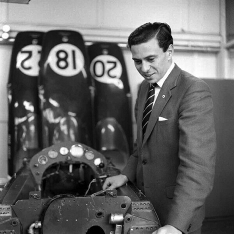 Jim, en costume, inspecte le chassis moocoque de la Lotus 25...